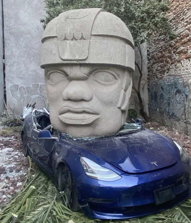 Obra de Chavis Marmol, donde una cabeza olmeca aplasta un Tesla